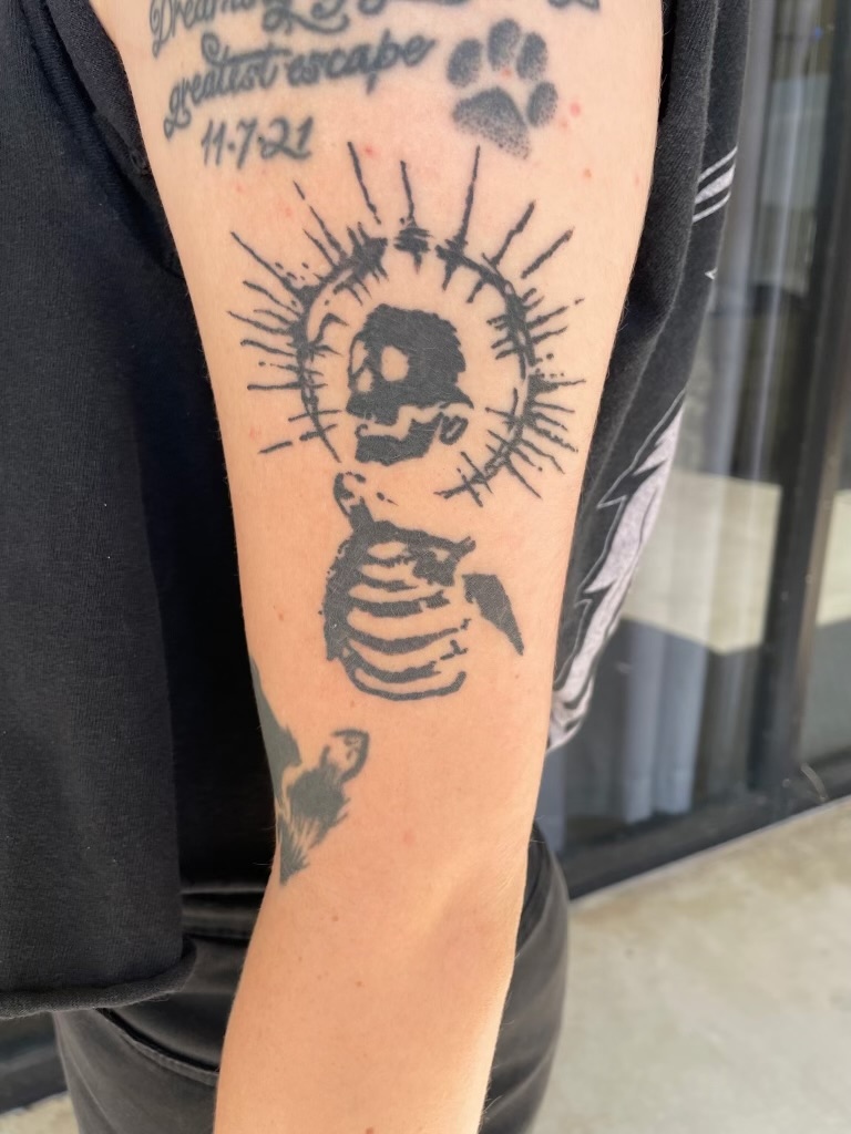 Blackwork halo skeleton bicep tattoo by Emma Bray