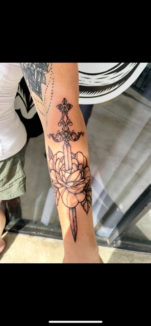Ornamental dagger through lotus forearm tattoo by Taylor Brown
