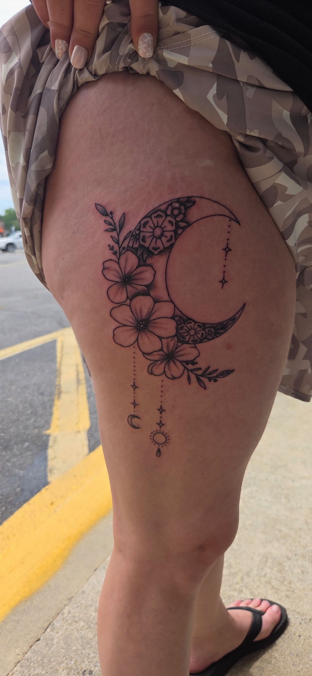 Ornamental crescent moon and florals thigh tattoo by Wesley Herring
